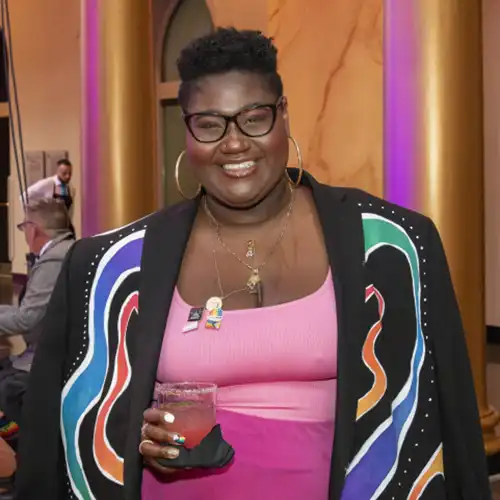 Tiffany Lyn from Pride365 Radio is seen holding a drink at a cocktail party.