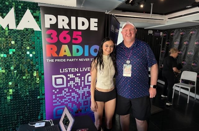 Artist Daya stands next to Houston by a Pride365 Radio Banner